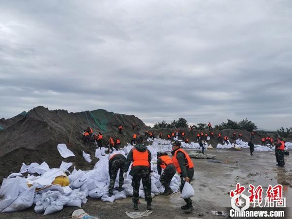 武警官兵正在用编织袋装运沙石